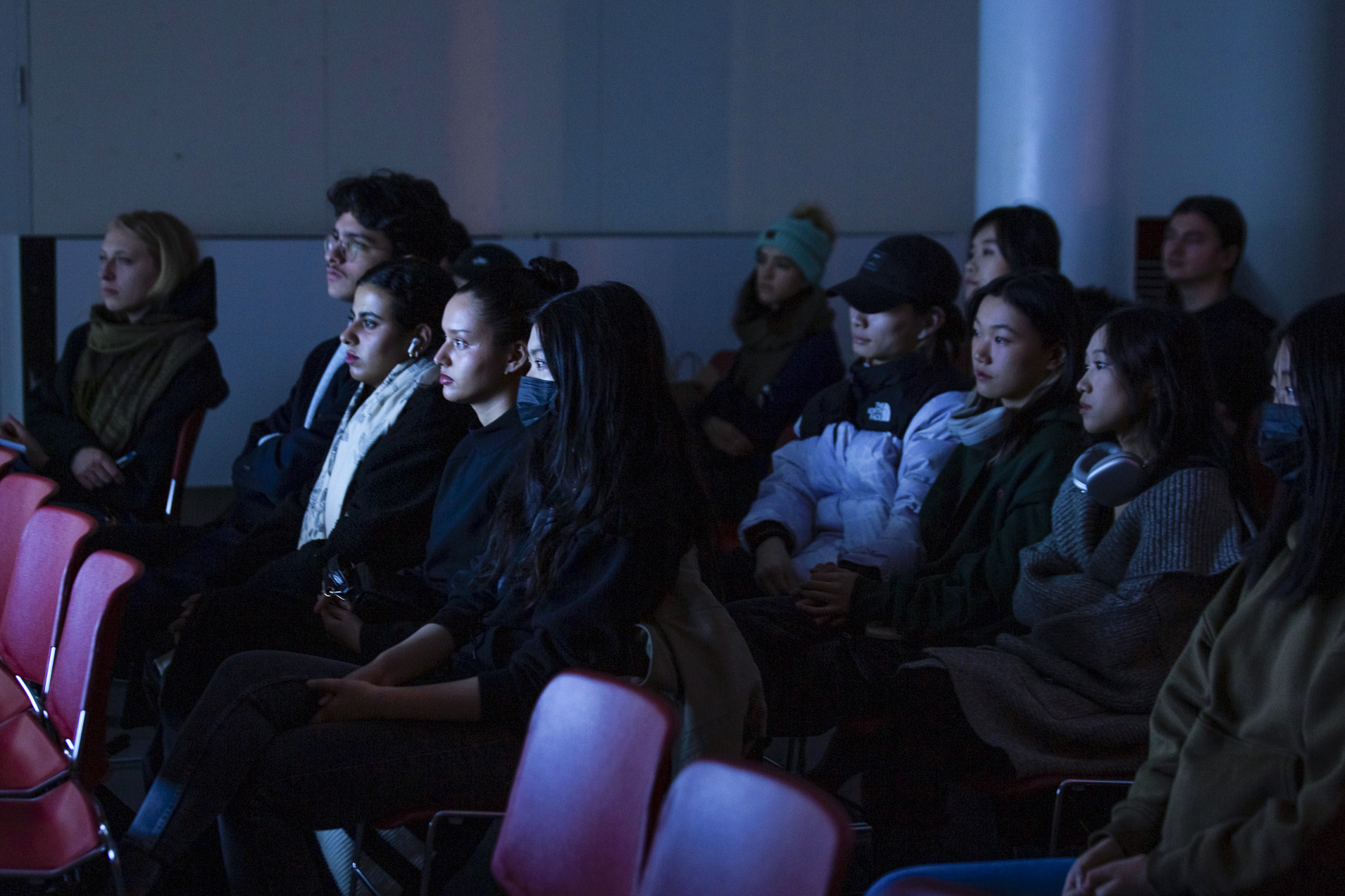 People looking at an object out of frame in a dark room while their faces are illuminated